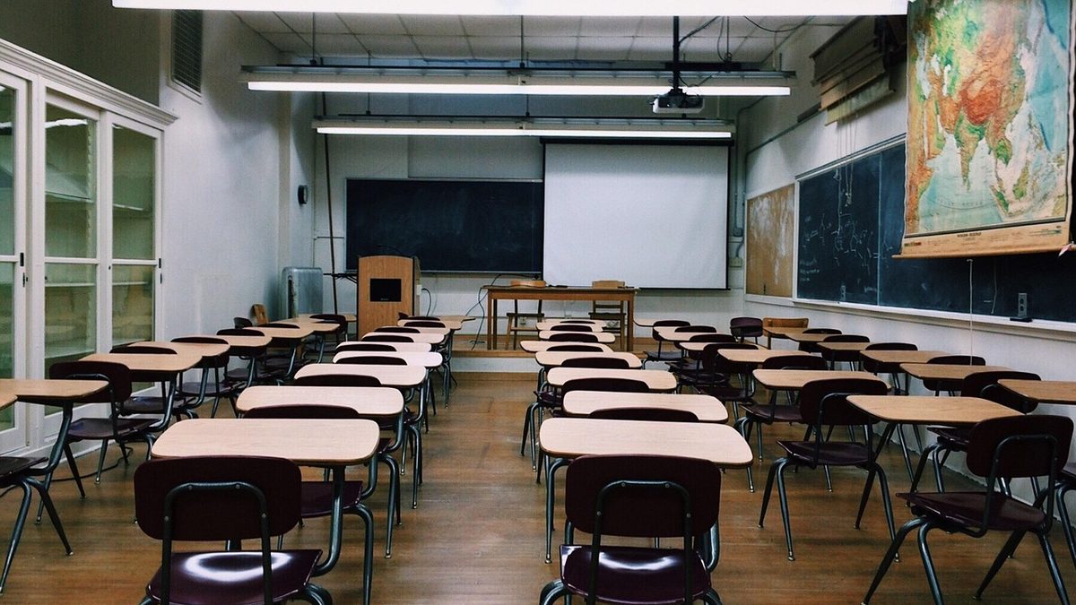 Sala de aula vazia, com carteiras enfileiradas e quadro
