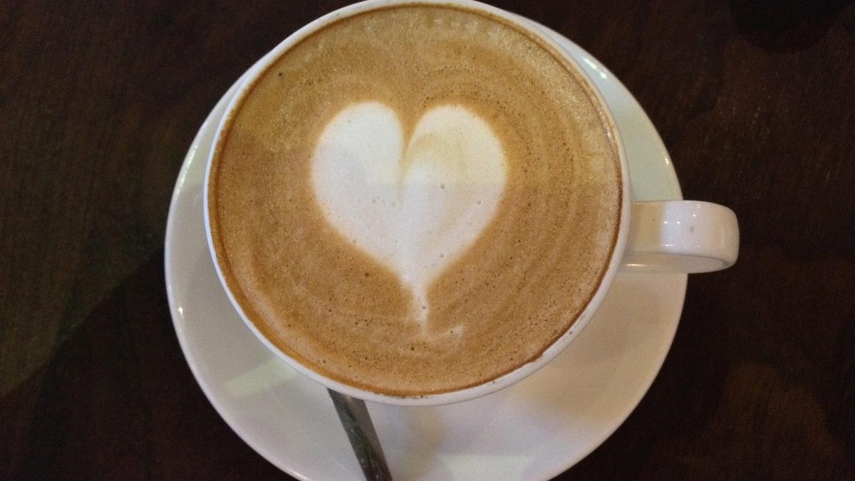Cappuccino com desenho de coração na espuma, servido em xícara branca