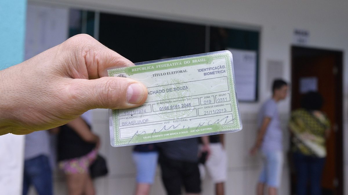 Eleitor segura o título de eleitor na fila da seção